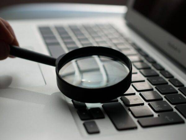 magnifying glass near gray laptop computer